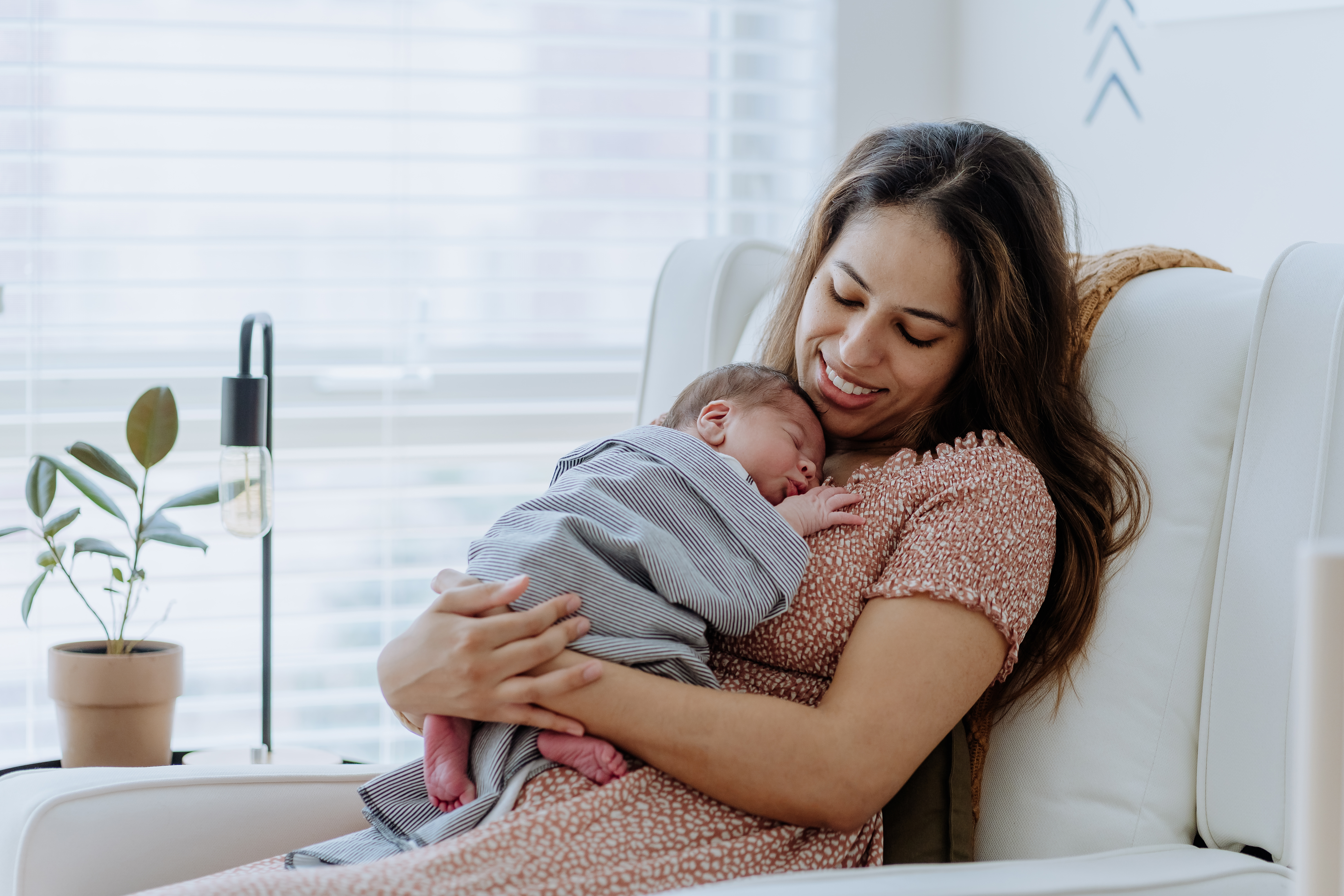 Mother holding her newborn in bright and cozy hospital room