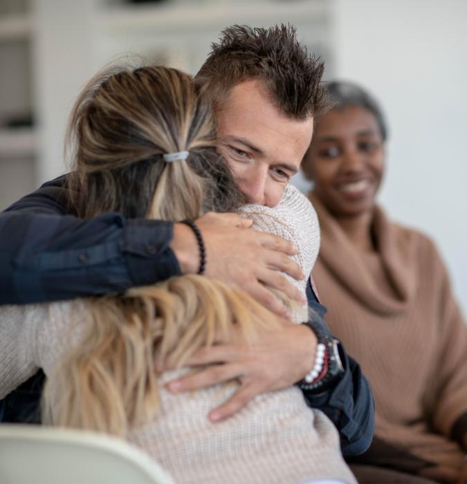 A group of adults take comfort in each other as they meet in therapy. 