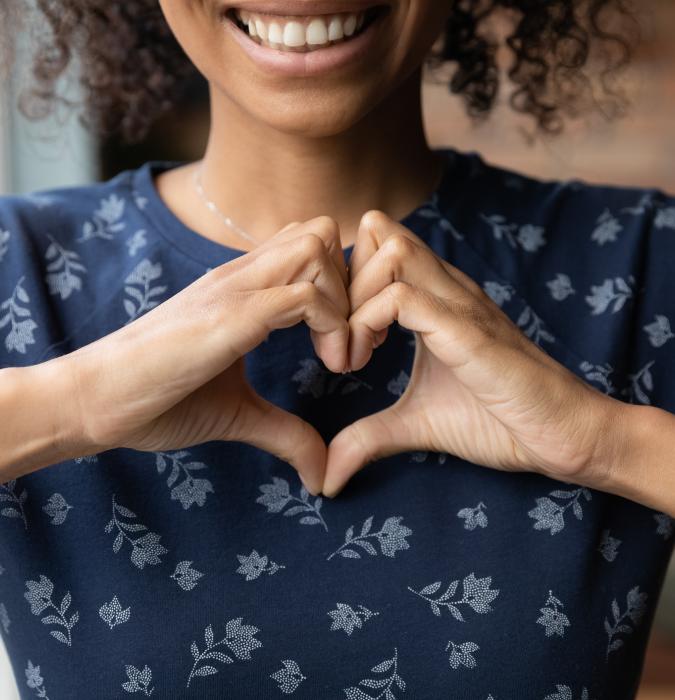 Smiling biracial woman show heart hand gesture