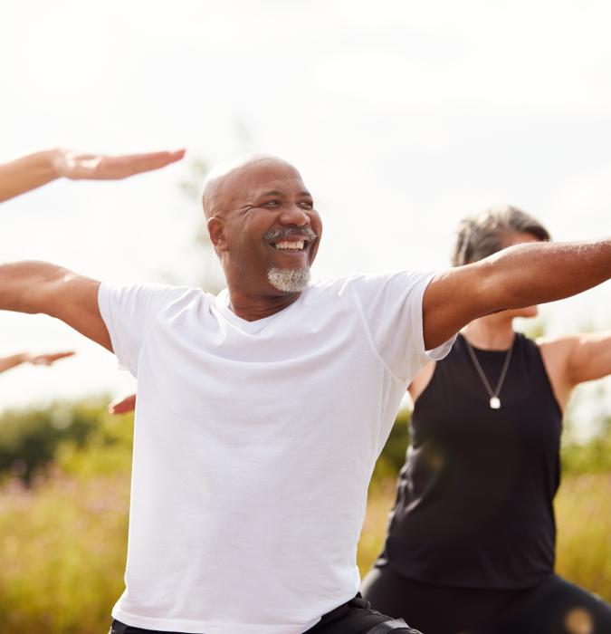 Group of middle aged people practicing yoga in the evening outdoors